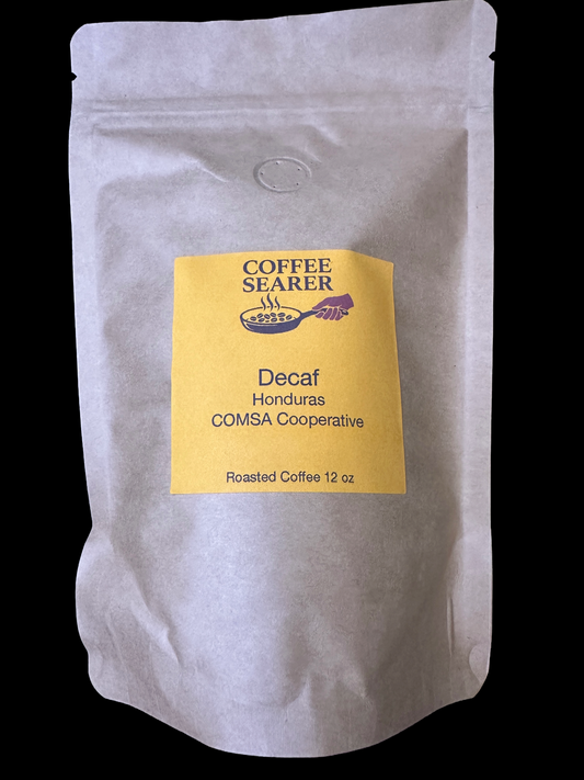 A 12 oz stand-up pouch of Coffee Searer Decaf Honduras coffee, featuring a yellow label on a white textured background, set against a solid black backdrop.
