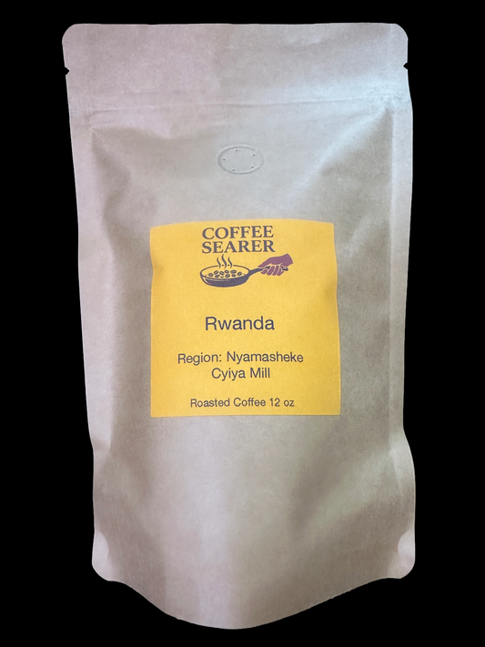 A stand-up pouch of Coffee Searer Rwanda roasted coffee, 12 oz, featuring a yellow label on a white bag, set against a solid black background.